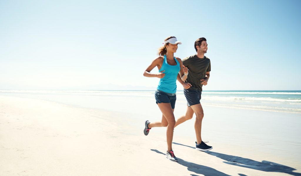 Shot of a personal trainer training a client on a beach