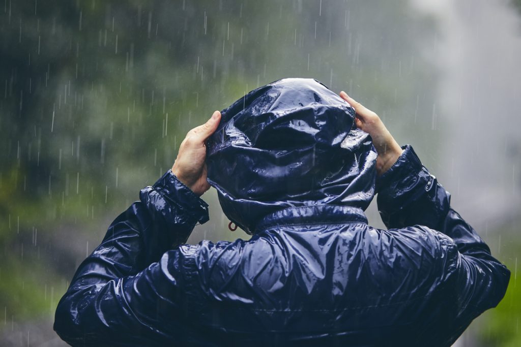 Person standing in rain wearing waterproof jacket.