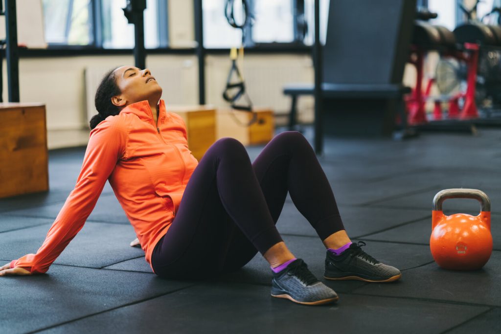 image of a tired gym goer resting on the floor with a kettlebell