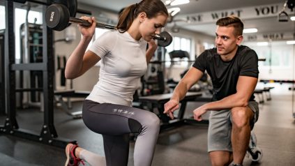 fitness professional training a client through lunges in the gym