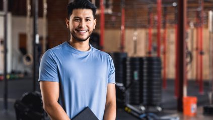 male fitness professional standing in the gym with a clipboard