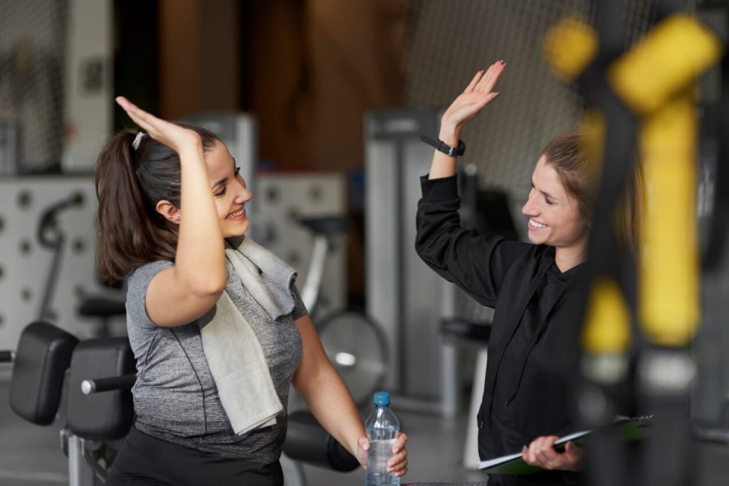image of a personal trainer and her client high-fiving in a gym