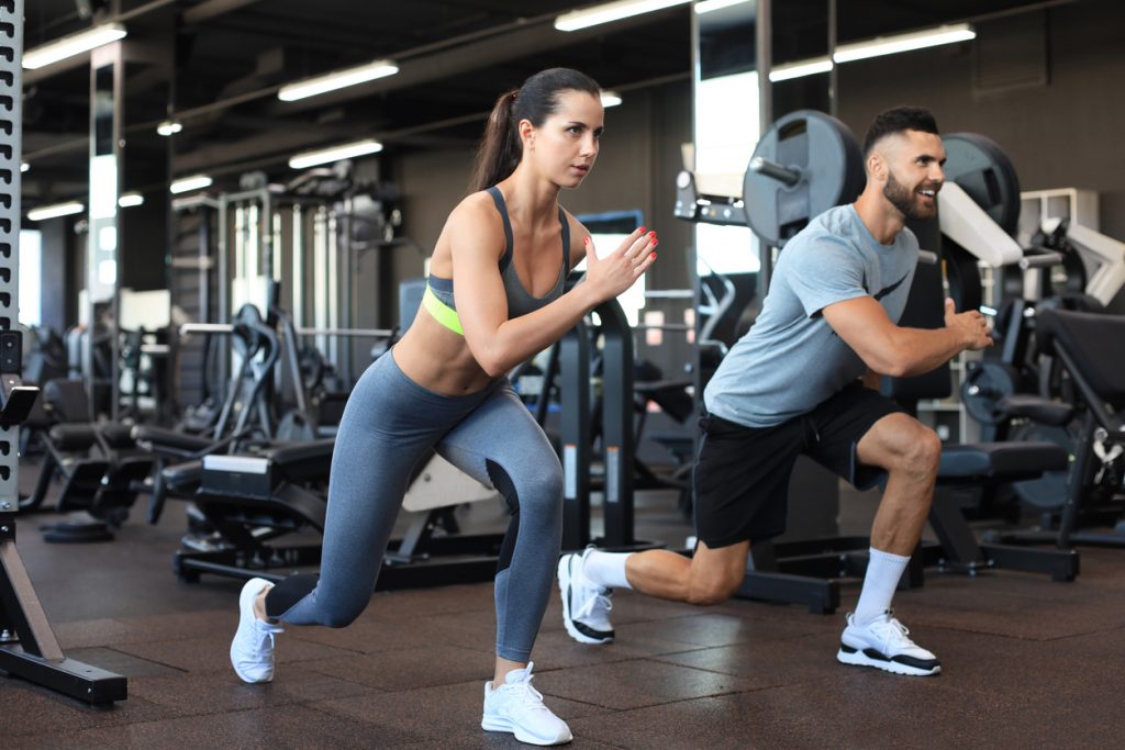 male and female trainers performing walking lunges