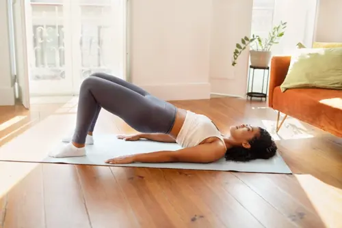 Woman doing bridge pose in her living room